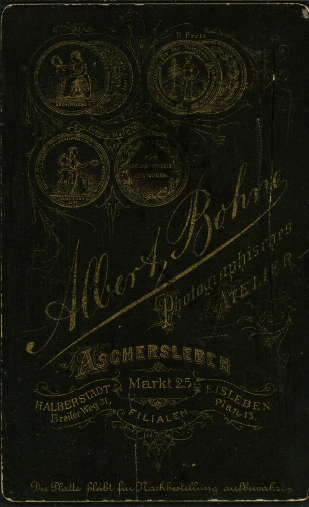 Reverse of a monochrome photographic portrait from between 1865 and the 1920s taken by A. Bohne, Markt 25, Aschersleben, Breiter Weg 31, Halberstadt, Plan 15, Eisleben