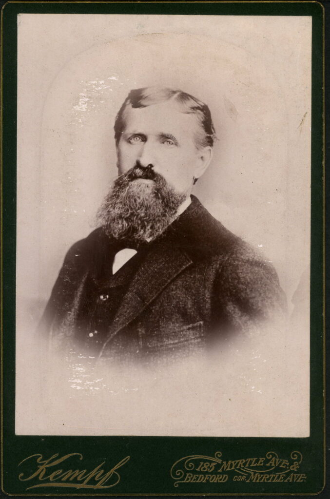 A monochrome photographic portrait from between 1865 and the 1920s taken in Kempf's Art Studios, 185 Myrtle Avenue, Brooklyn, NY