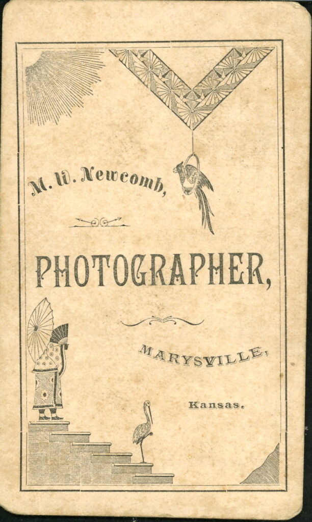 Reverse of a monochrome photographic portrait from between 1865 and the 1920s taken by M. W. Newcomb, Marysville, Kansas